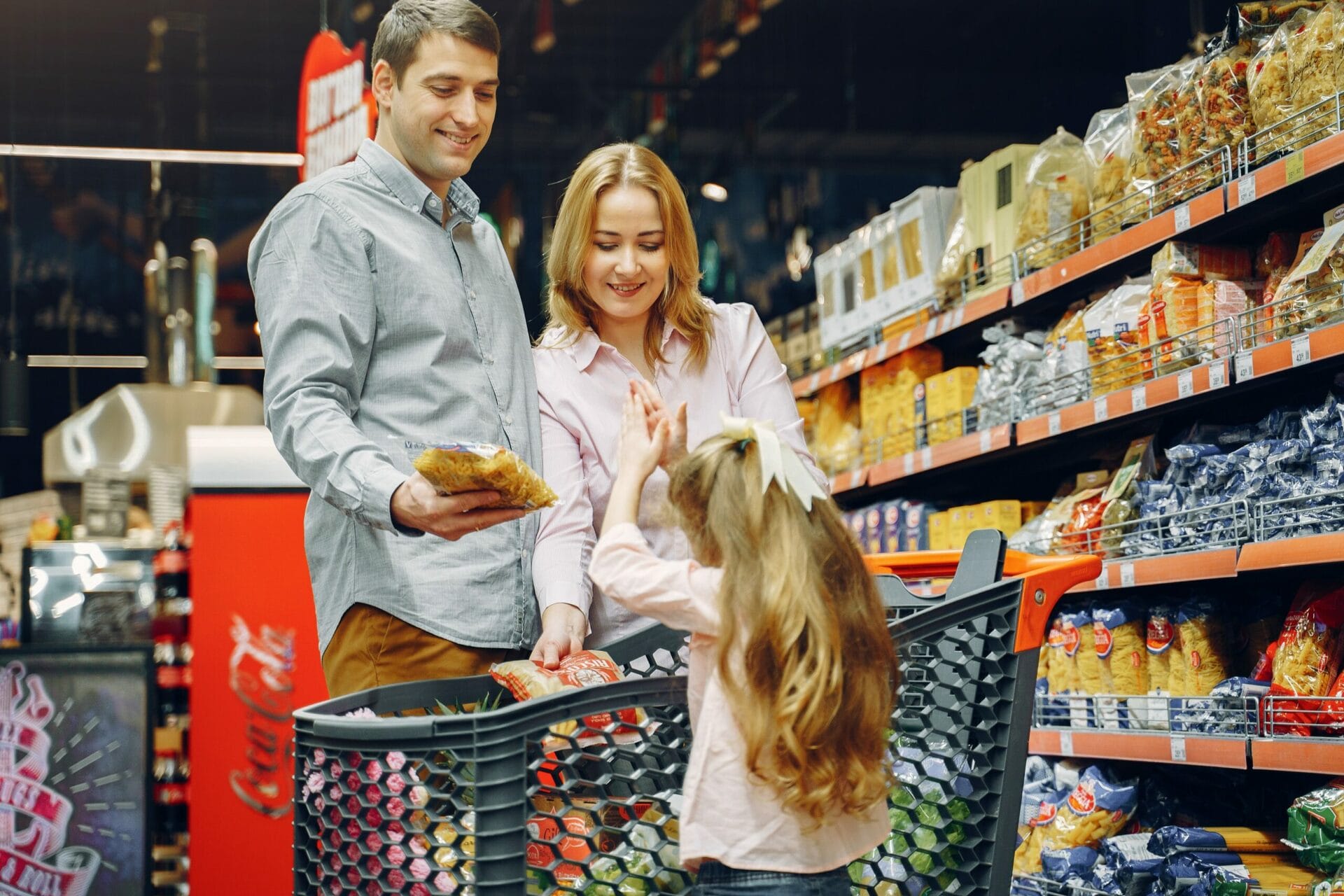 A family shopping for groceries with a Kroger shopping cart.