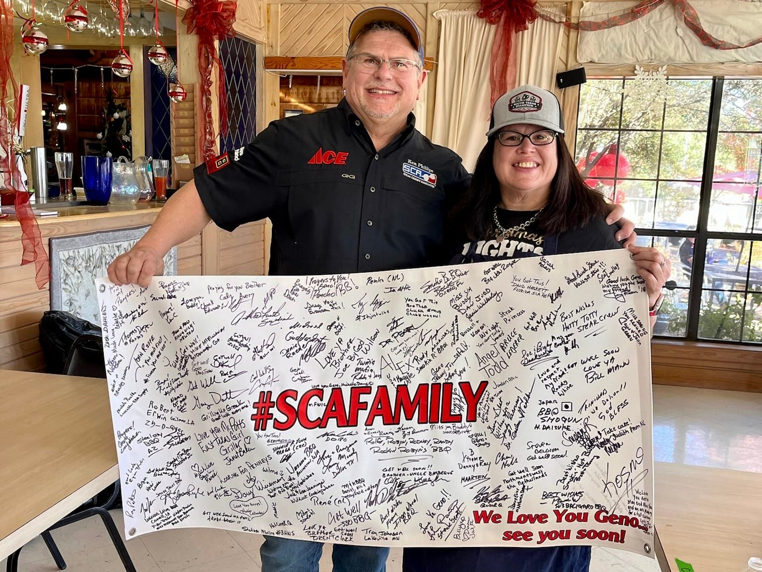 Two cooks holding a signed SCA Family banner at the Winter Wonderland Cookoff